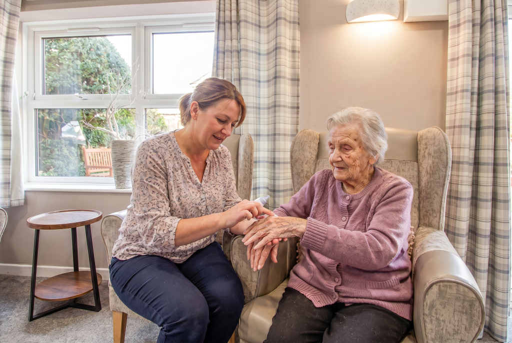 Lady rubbing cream onto an elderly ladies hands